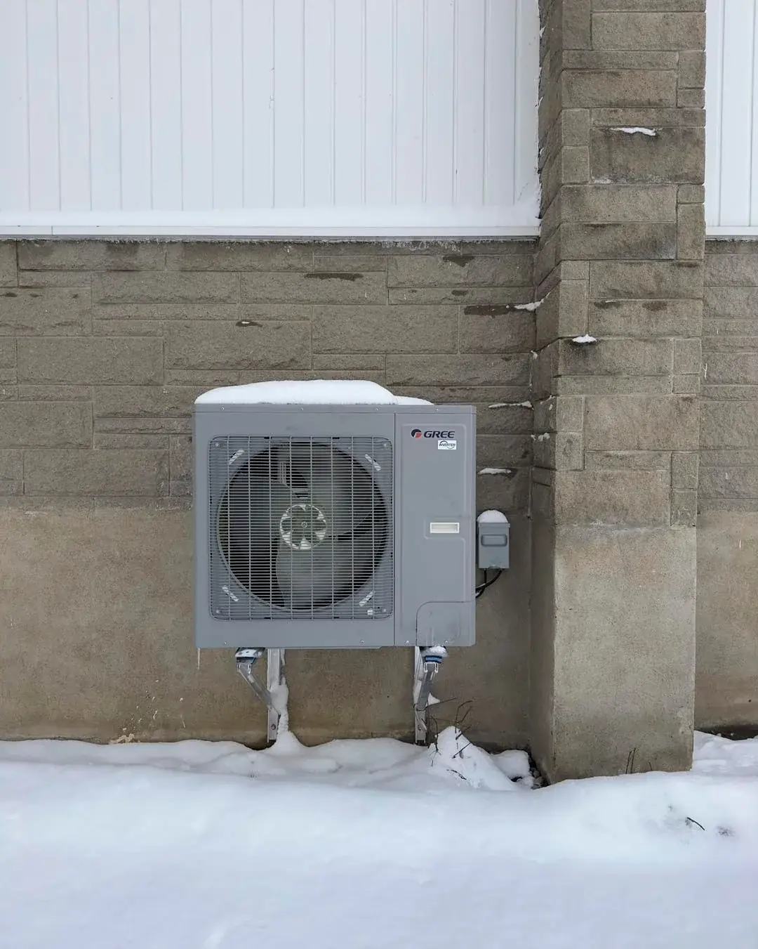 Thermopompe Gree installée l'hiver, entourée de neige
