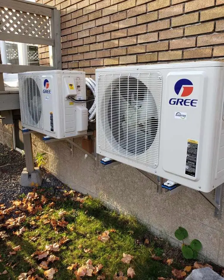 Deux condenseurs Gree fixés au mur d'une maison en brique pour un système multi-zone