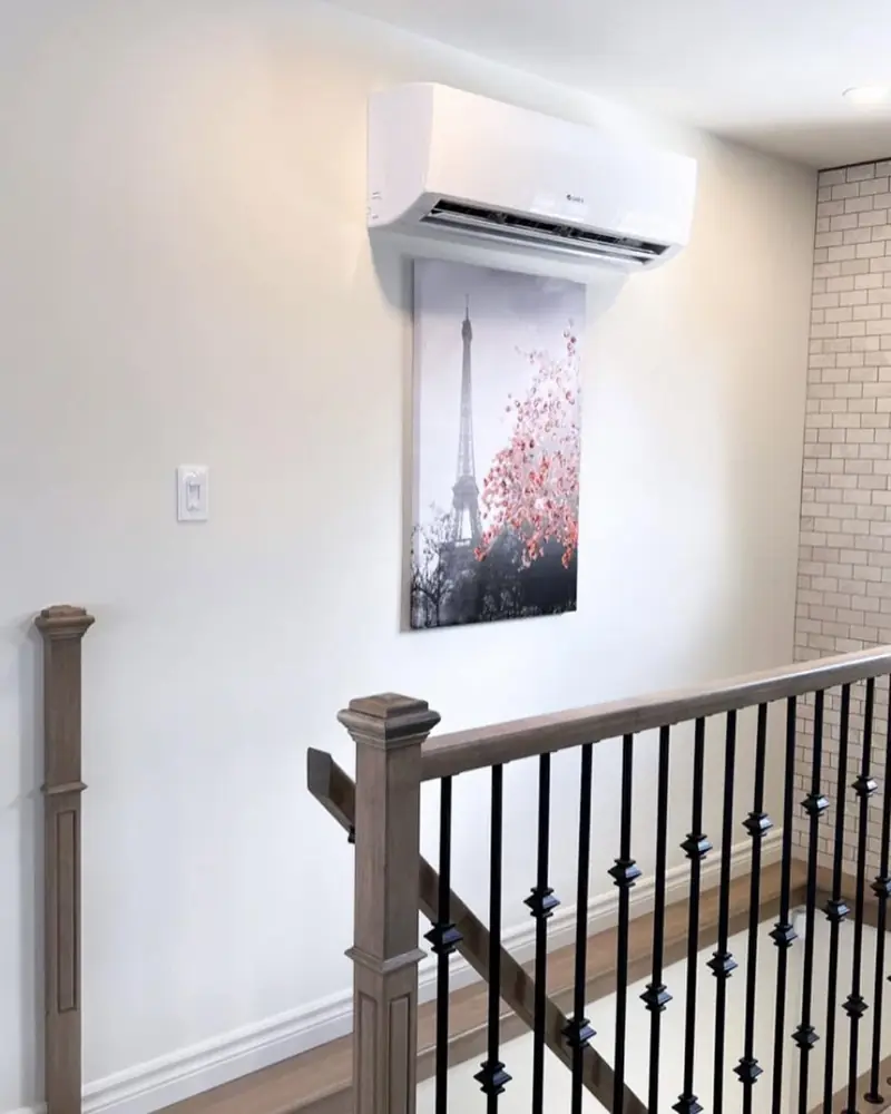 Tête murale de thermopompe installée au-dessus d'un escalier intérieur