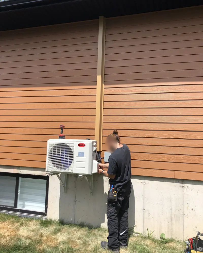 Technicien de Groupe RENOX qui raccorde un condenseur fixé sur un support mural